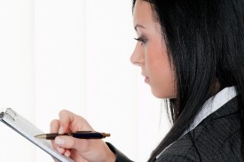 business woman taking notes on clipboard