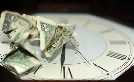 time is money crumpled dollar bills on clock