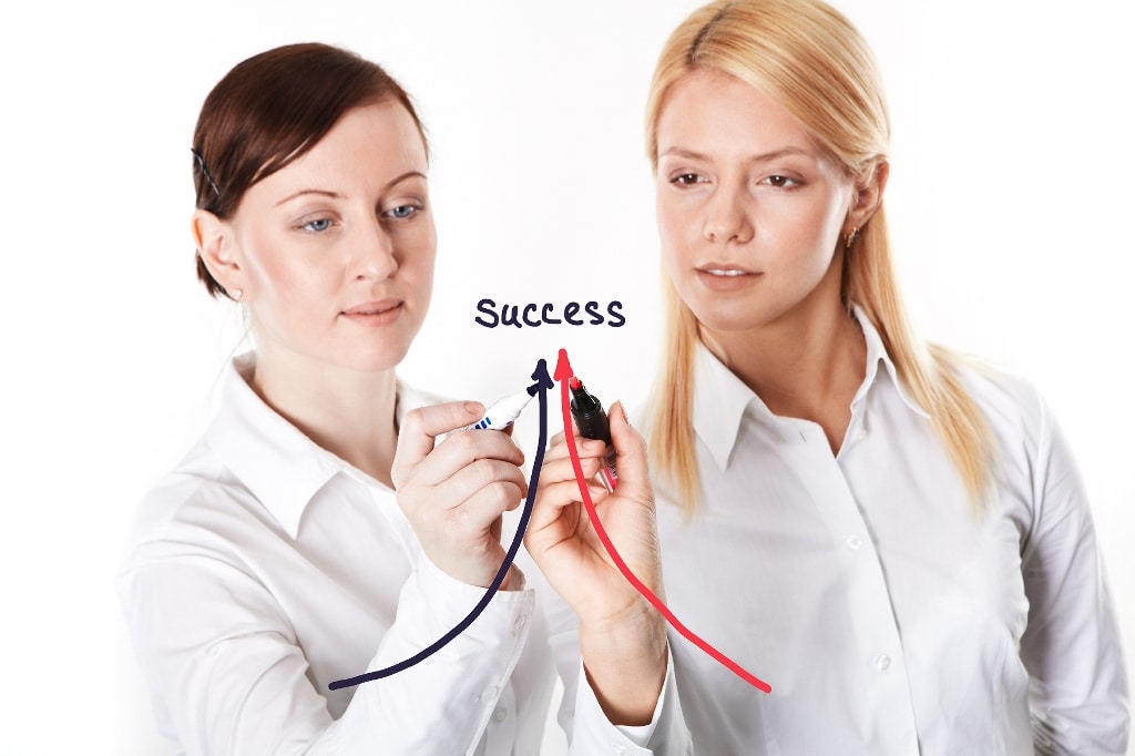 two business women writing success arrows