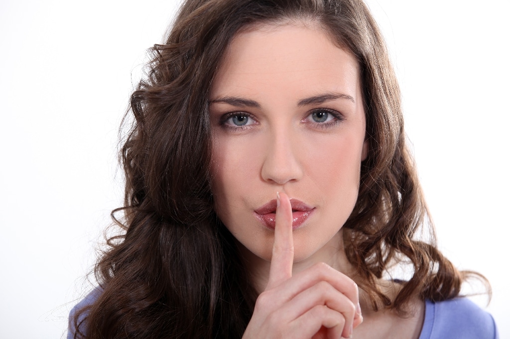 secret quiet whisper woman with finger over mouth
