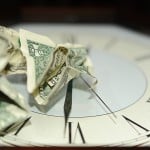 time is money crumpled dollar bills on clock
