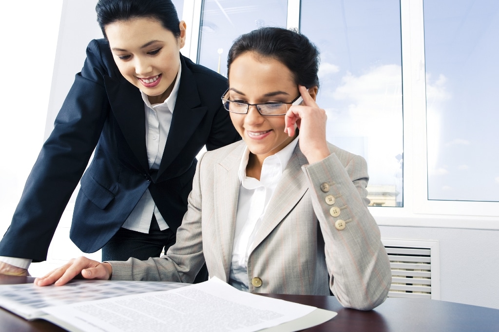 two diverse business women reviewing documents at desk