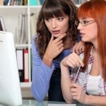 young business women looking at computer screen thinking problem