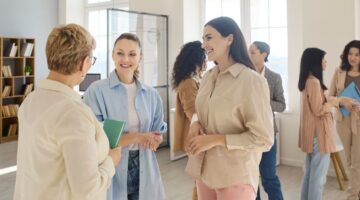 Professional women laughing during a meeting after answering funny icebreaker questions