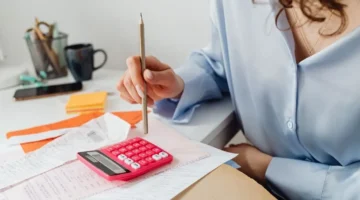 woman entrepreneur doing finances with calculator and receipts