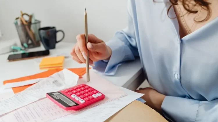 woman entrepreneur doing finances with calculator and receipts
