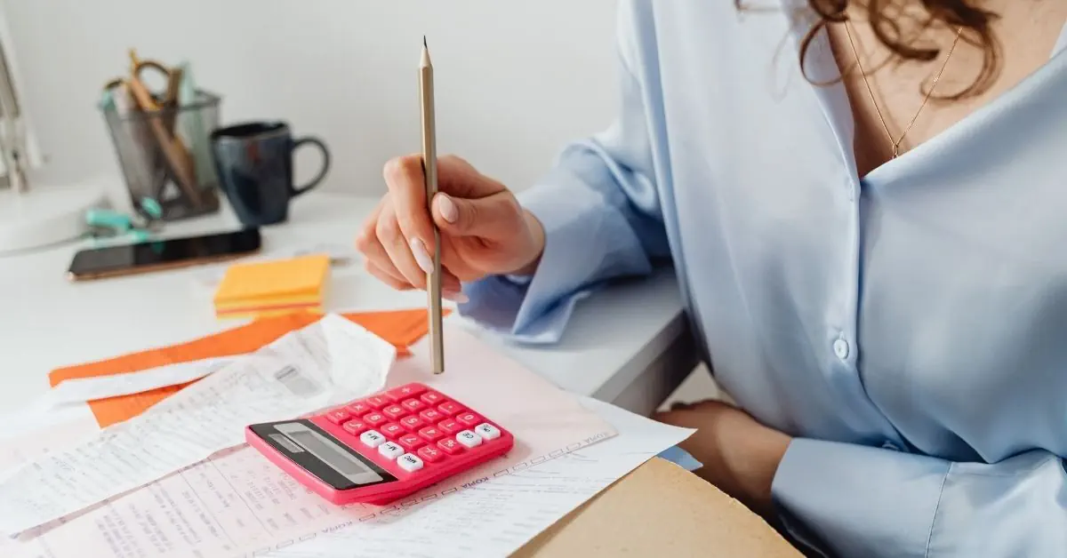 woman entrepreneur doing finances with calculator and receipts