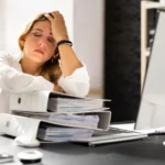 businesswoman at desk showing physical signs of workplace stress