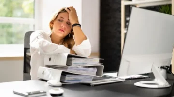 businesswoman at desk showing physical signs of workplace stress