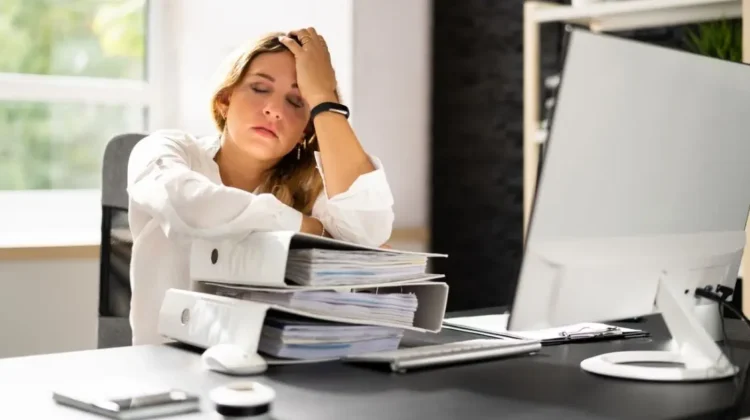 businesswoman at desk showing physical signs of workplace stress